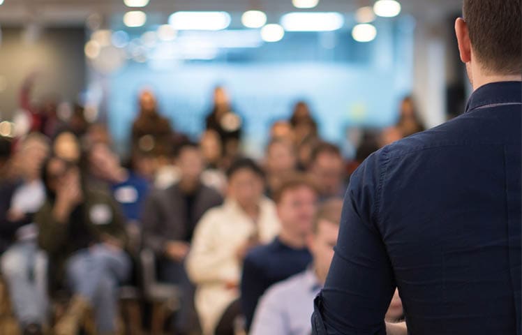 Speaker addressing group  Businessman entrepreneur giving a lecture to a sold-out crowd in a lecture hall  Speaker talking in seminar  Speaker at business conference or presentation stock photo  Male CEO talking during a business presentation in a board room  Copy space  Business coach concept 