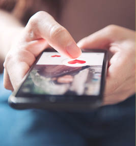 Finger of woman pushing heart icon on screen in mobile smartphone application  Online dating app, valentine's day concept 