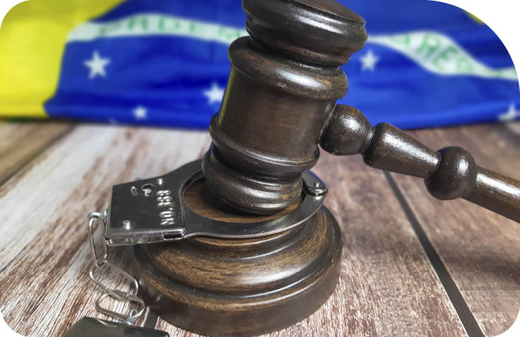 Judge's gavel with handcuffs and the Brazilian flag.