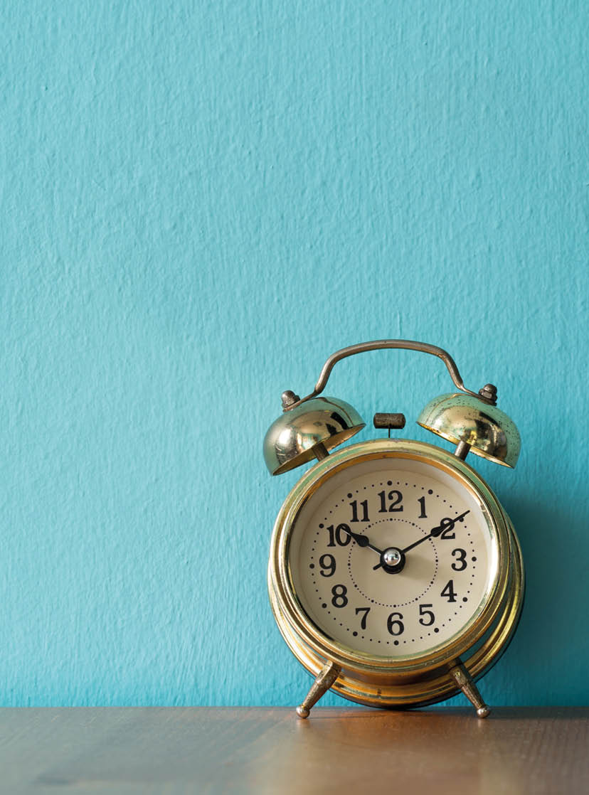 Gold vintage alarm clock on the wood table  the background is blue and copy space for text