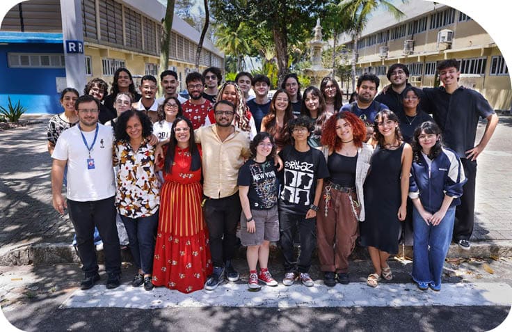 Grupo de pessoas sorrindo posando para foto ao ar livre em um ambiente com rvores e pr dios ao fundo.  Description generated by AI