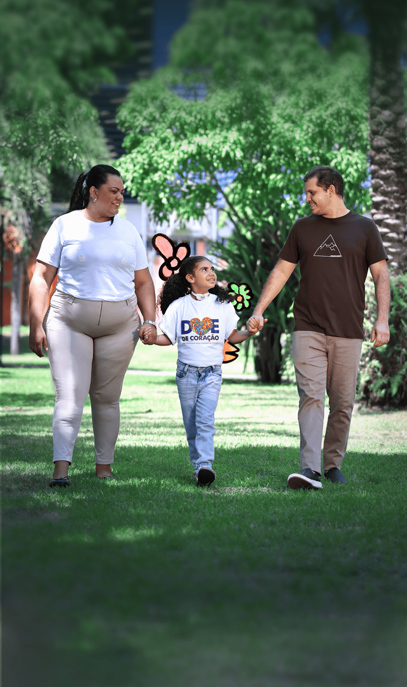Pessoa adulta vestindo camiseta branca e cal a clara, pessoa adulta vestindo camiseta marrom e cal a clara, e crian a com camiseta branca e cal a jeans caminhando de m os dadas em parque com rvores ao fundo.  Description generated by AI