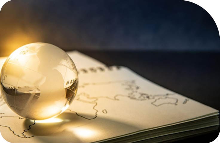 Uma esfera de vidro transparente est posicionada sobre um mapa desenhado em papel, com luz suave iluminando a cena.  Description generated by AI