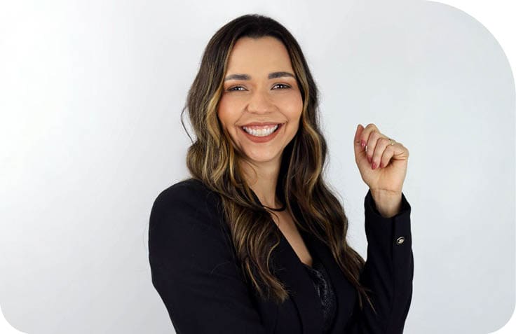 Pessoa adulta com cabelo longo ondulado usando blazer preto sorrindo e com bra o cruzado em fundo branco. Description generated by AI