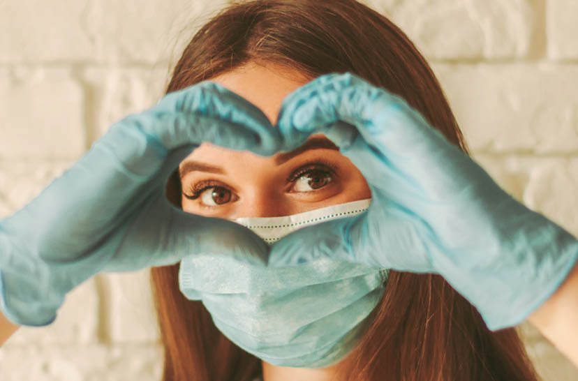 Banner young woman in protective face mask and medical gloves gesturing love shape sign  Happy girl in medical face mask and gloves looking through hands in form of heart symbol  Health care, COVID-19