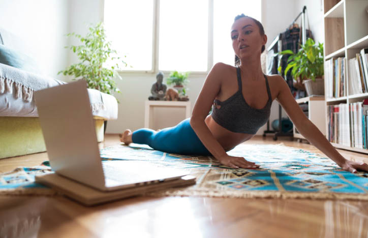 Young Caucasian woman doing yoga at home  Learning exercise from tutorials on her laptop  Practicing meditation and breathing exercise at home 