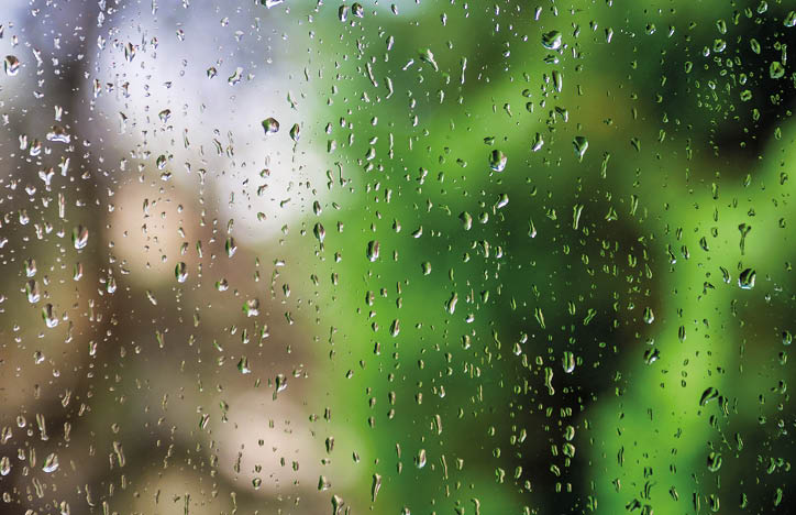 Water drops on window glass with blur garden background