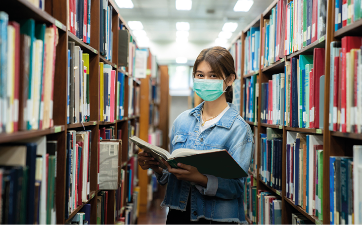 Asian university student girl wearing face protective medical mask for protection from virus disease reading book at library  Education, high school, university, learning and people concept