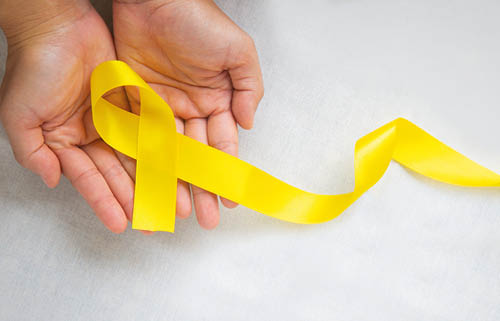 Hand holding Yellow ribbon on white background, copy space  Bone cancer, Sarcoma Awareness, childhood cancer, cholangiocarcinoma, gallbladder cancer, world Suicide Prevention Day  Health concept 