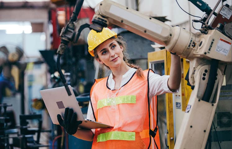 Female industrial engineer or technician worker in hard helmet and uniform using laptop checking on robotic arm machine  woman work hard in heavy technology invention industry manufacturing factory